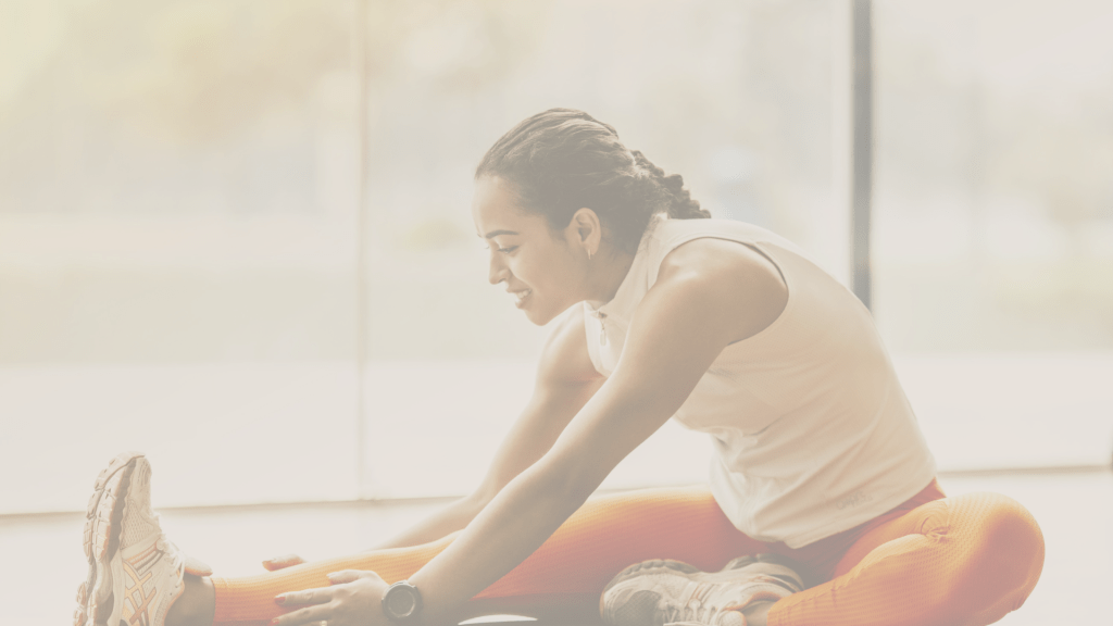 A woman stretching out her leg on a mat in the gym